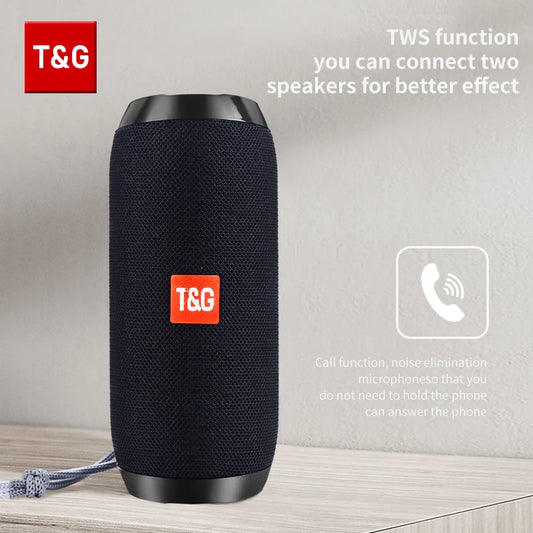 Black T&G branded Bluetooth speaker on a wooden surface with a light gray background
